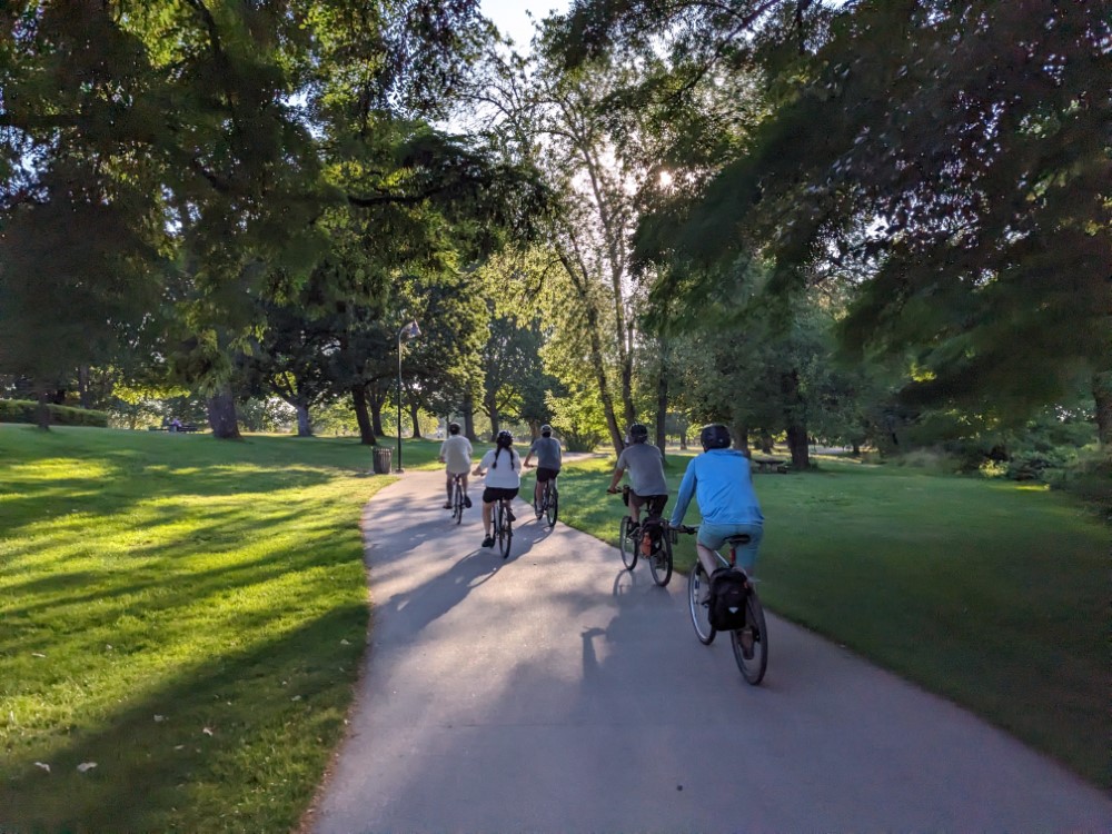 A group of people riding bikes on a paved path through a park.